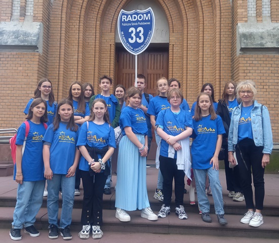 Uczniowie w niebieskich koszulkach stojący przed Katedrą