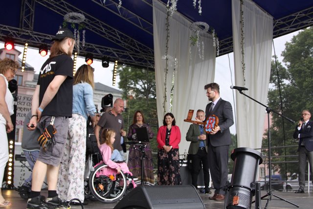 Niepełnosprawne osoby na wózkach na scenie, prezydent wręcza im klucz