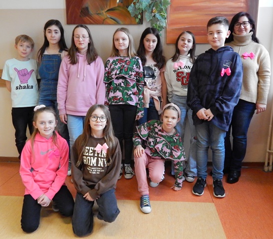 Uczniowie i nauczycielka w ubraniach w kolorze różowym i z kokardkami różowymi