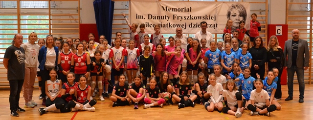 Dziewczynki wraz z trenerami biorące udział w Memoriale, wraz z nimi Goście i Dyrektor PSP 33, nad nimi baner z nazwą Memoriału