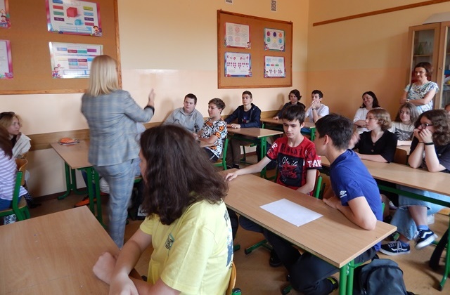 Uczniowie siedzący w sali i nauczyciele
