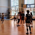 Uczniowie grają w siatkówkę, w sali gimnastycznej