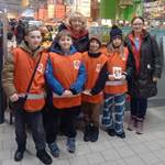 Wolontariusze w strojach pomarańczowych wraz z nauczycielką, w markecie