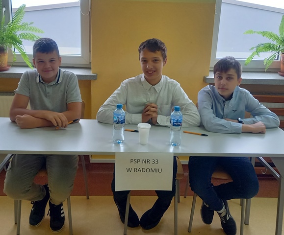 Trzej chłopcy siedzący za stołem