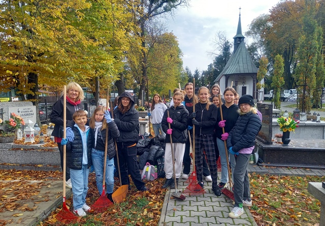 Uczniowie sprzątający na cmentarzu