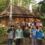 Uczniowie w lesie na tle drewnianej chaty
