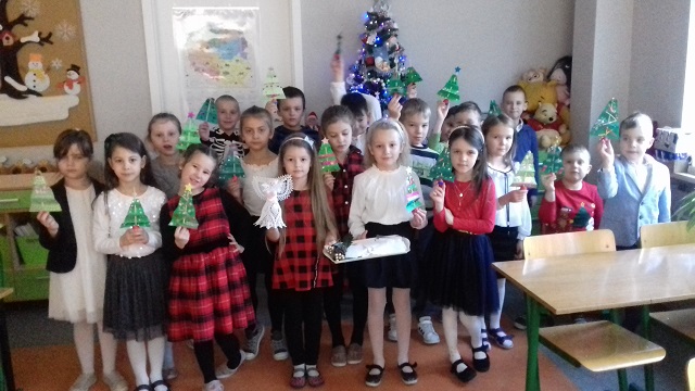 Dzieci trzymające ozdoby świąteczne, stojące w sali