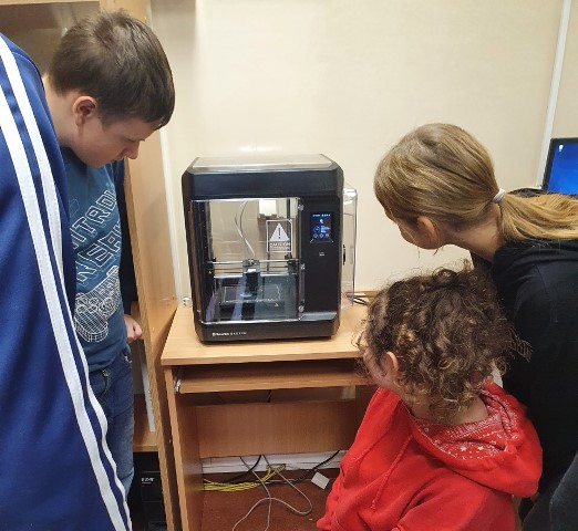 Uczniowie wpatrzeni w drukarkę 3D