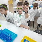 Uczniowie w białych fartuchach podczas robienia eksperymentów