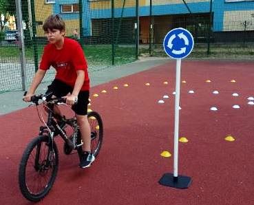 Uczeń na rowerze przy znaku drogowym mobilnego miasteczka