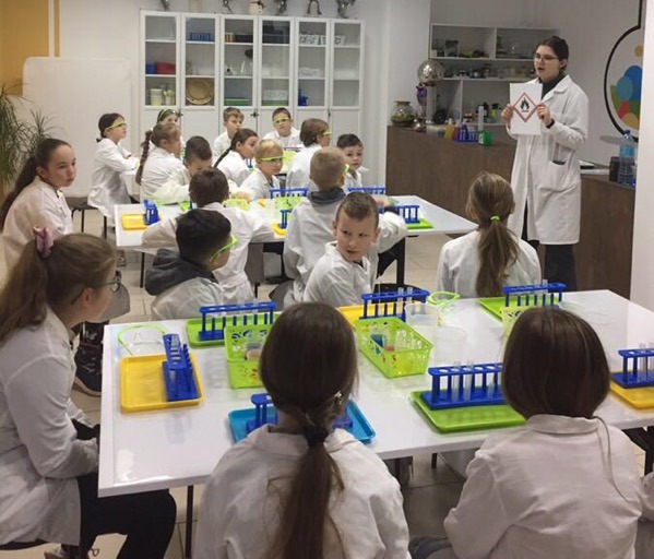 Uczniowie ubrani w białe fartuchy, podczas eksperymentów