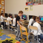 Dzieci siedzące przy komputerach w świetlicy