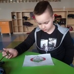 Chłopiec siedzący przy stoliku i wykonujący rysunek